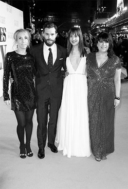 Actors James Dornan and Dakota Johnson are seen dressed in a tux and a gown respectively, posing for photos with Sam Taylor-Johnson and E. L. James, who are also in gowns. Crowds are seen behind them.